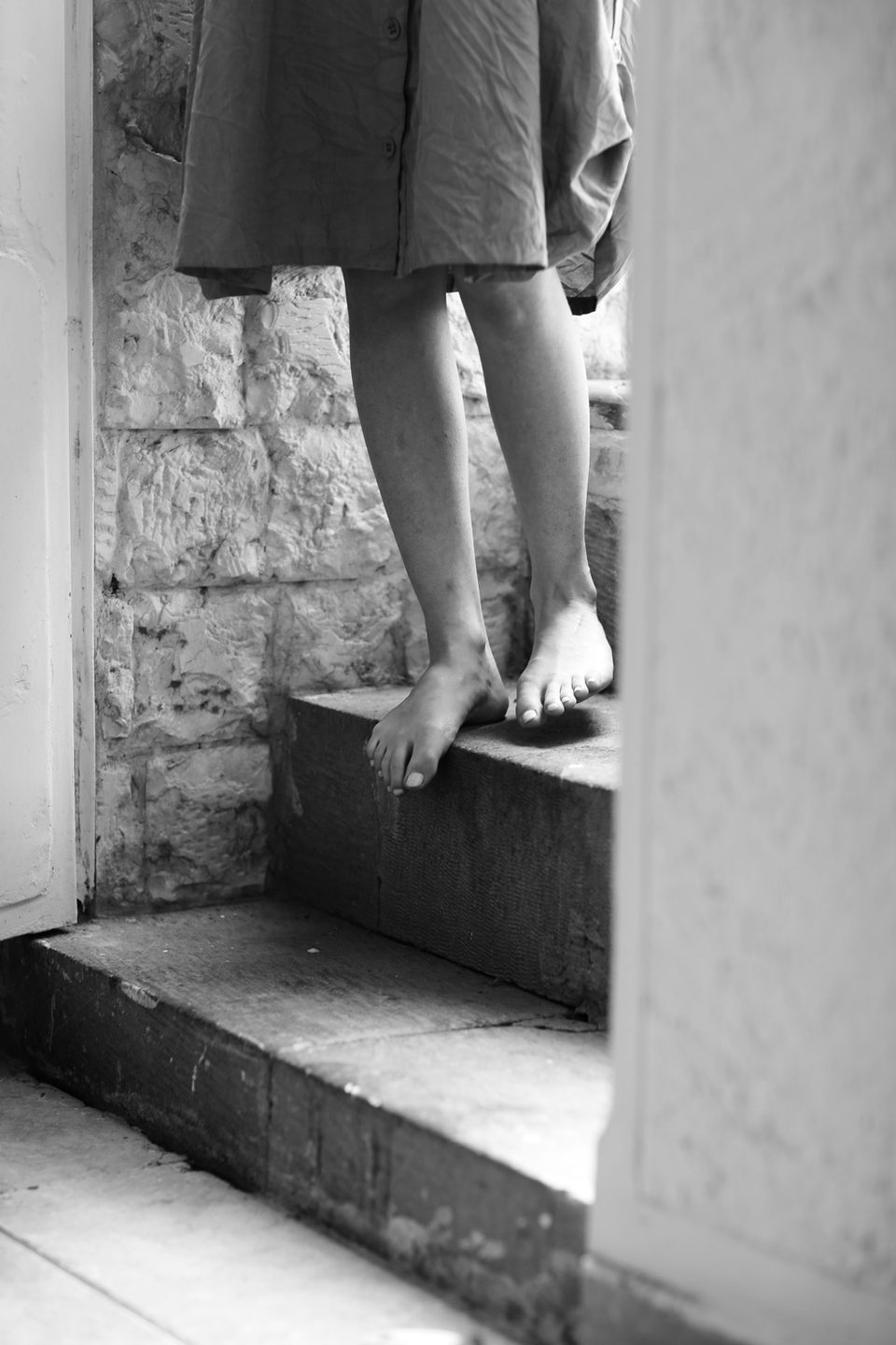Bare feet standing on worn stone steps, black and white