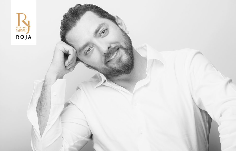 Bahram Radan in a white shirt resting his head on his hand, campaign portrait for RojaShop