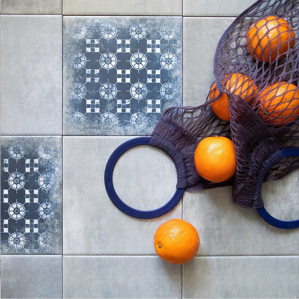 Oranges in a string bag on blue and white patterned tiles