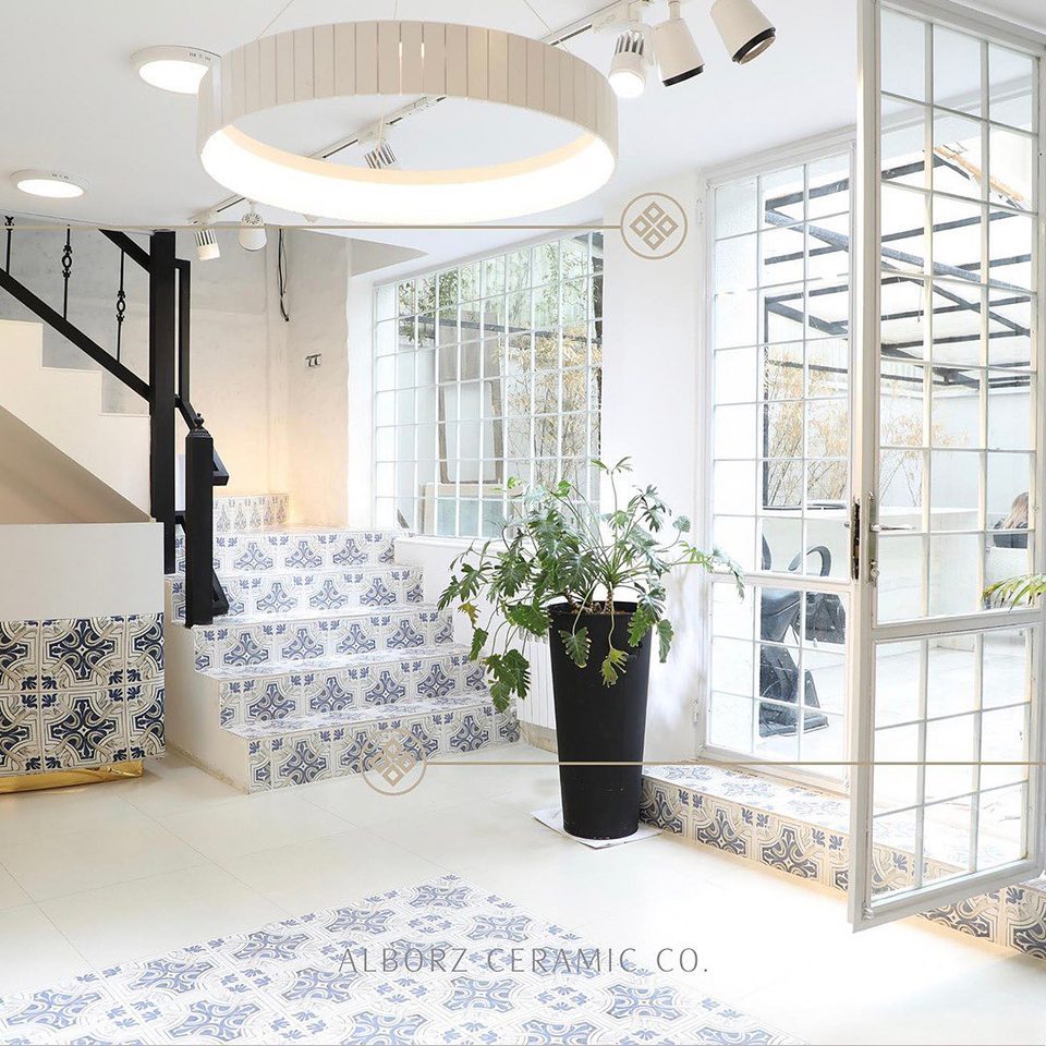 A white stairwell with blue and white patterned tiles on the steps and floor