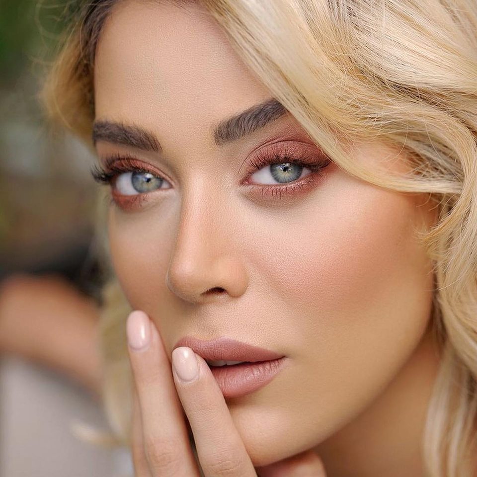 Close beauty portrait of a blonde woman with her fingertips at her lips
